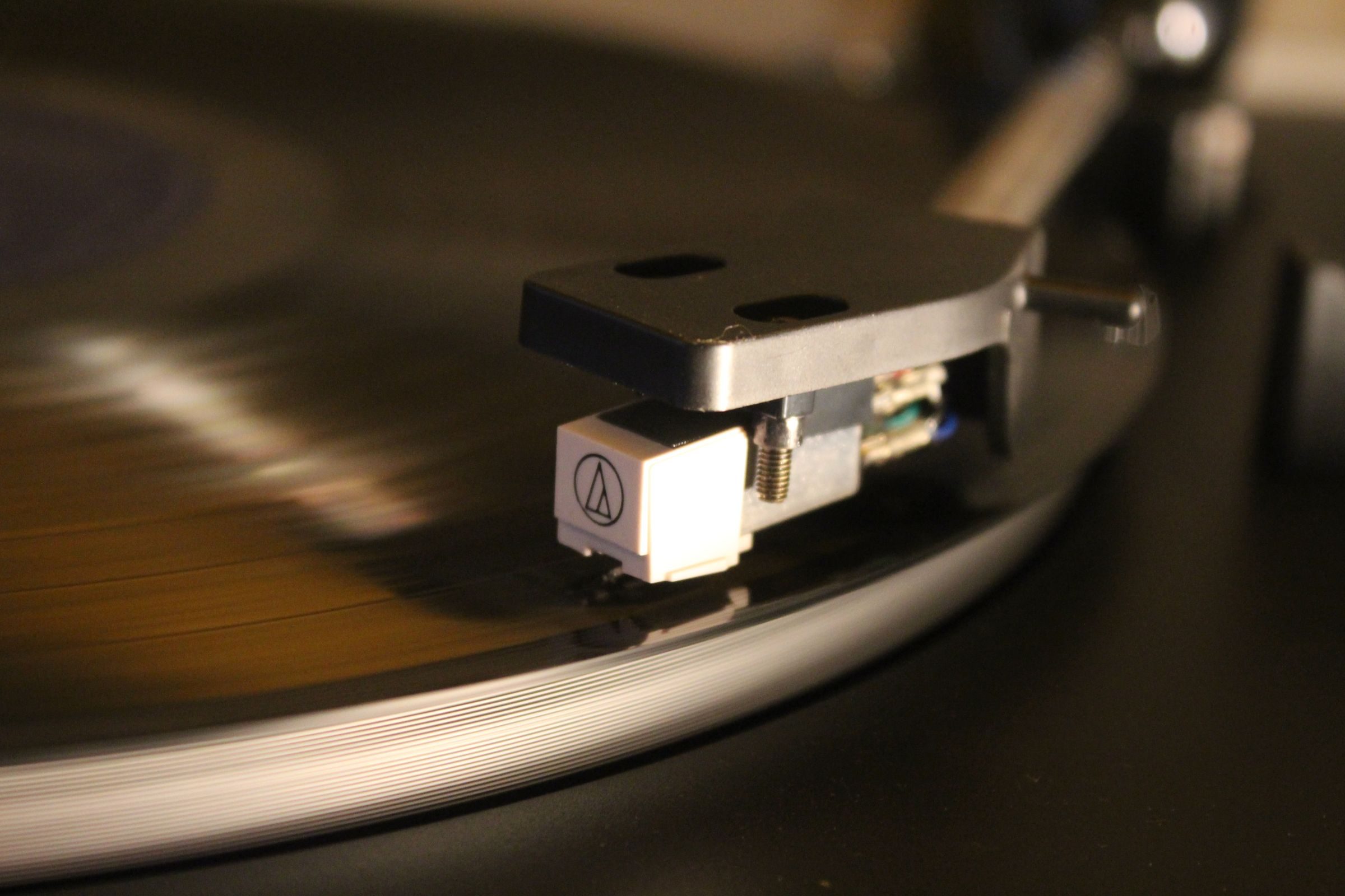 Platine vinyle avec bras et cellule posés sur un disque noir en rotation